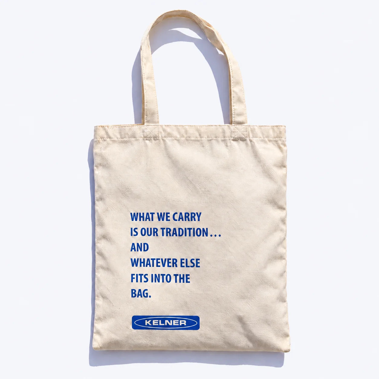 Back of the cream canvas tote with the What We Carry statement and KELNER mark in cobalt
