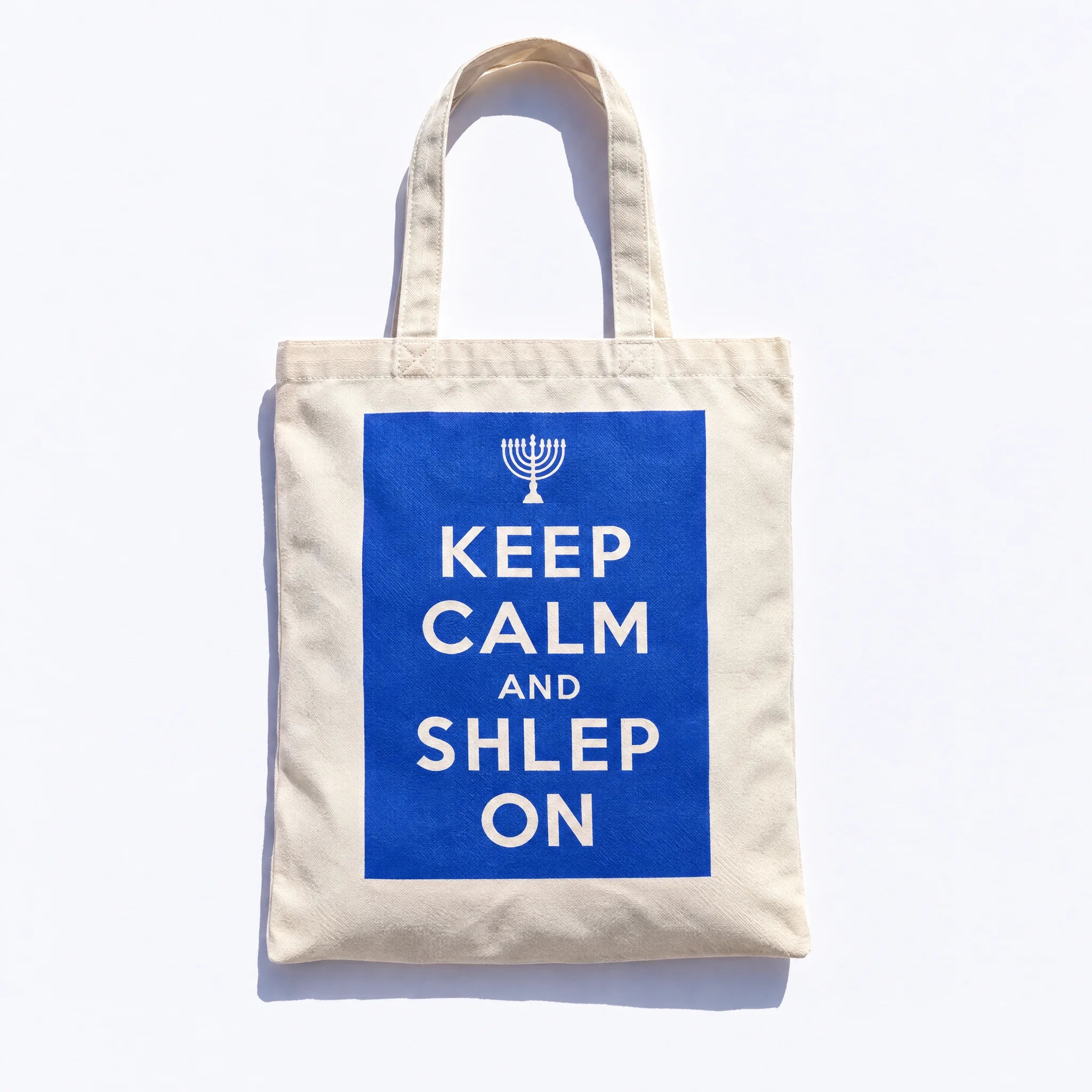 Front of the cream canvas tote with a cobalt panel, cream menorah, and Keep Calm and Shlep On lettering
